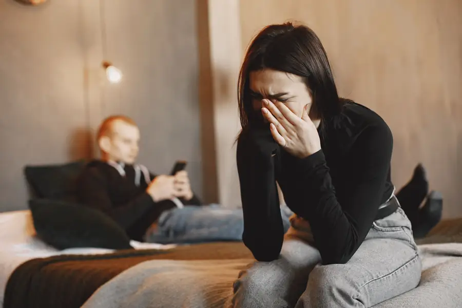 Una mujer llora con la cara entre las manos mientras su pareja mira el teléfono