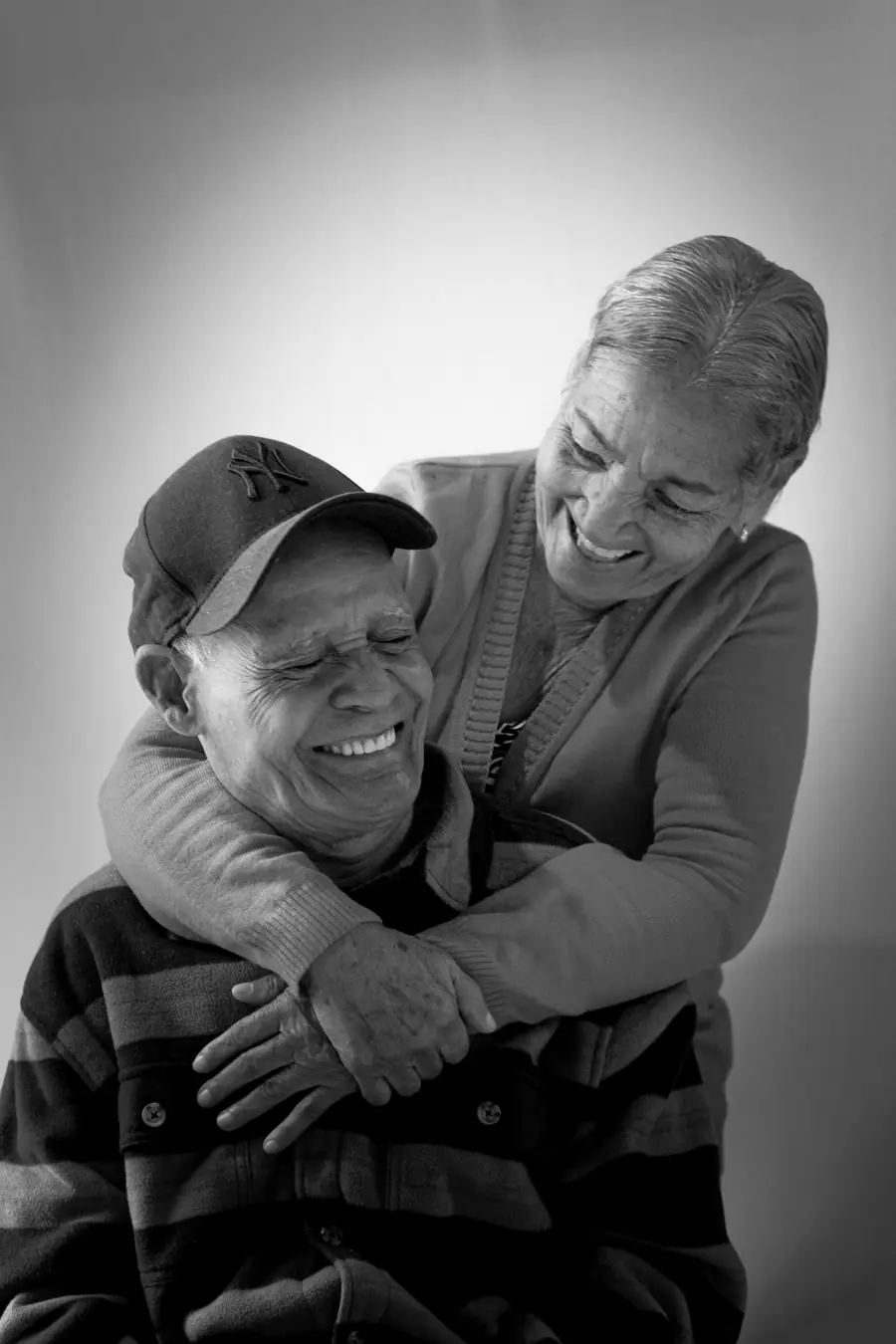 Una pareja mayor abrazada y riendo, en blanco y negro