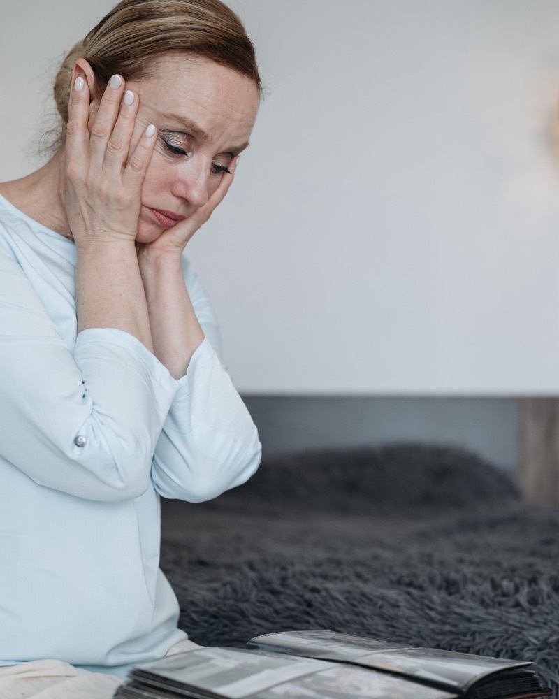 Una madre sentada en la cama, con la cabeza apoyada en las manos